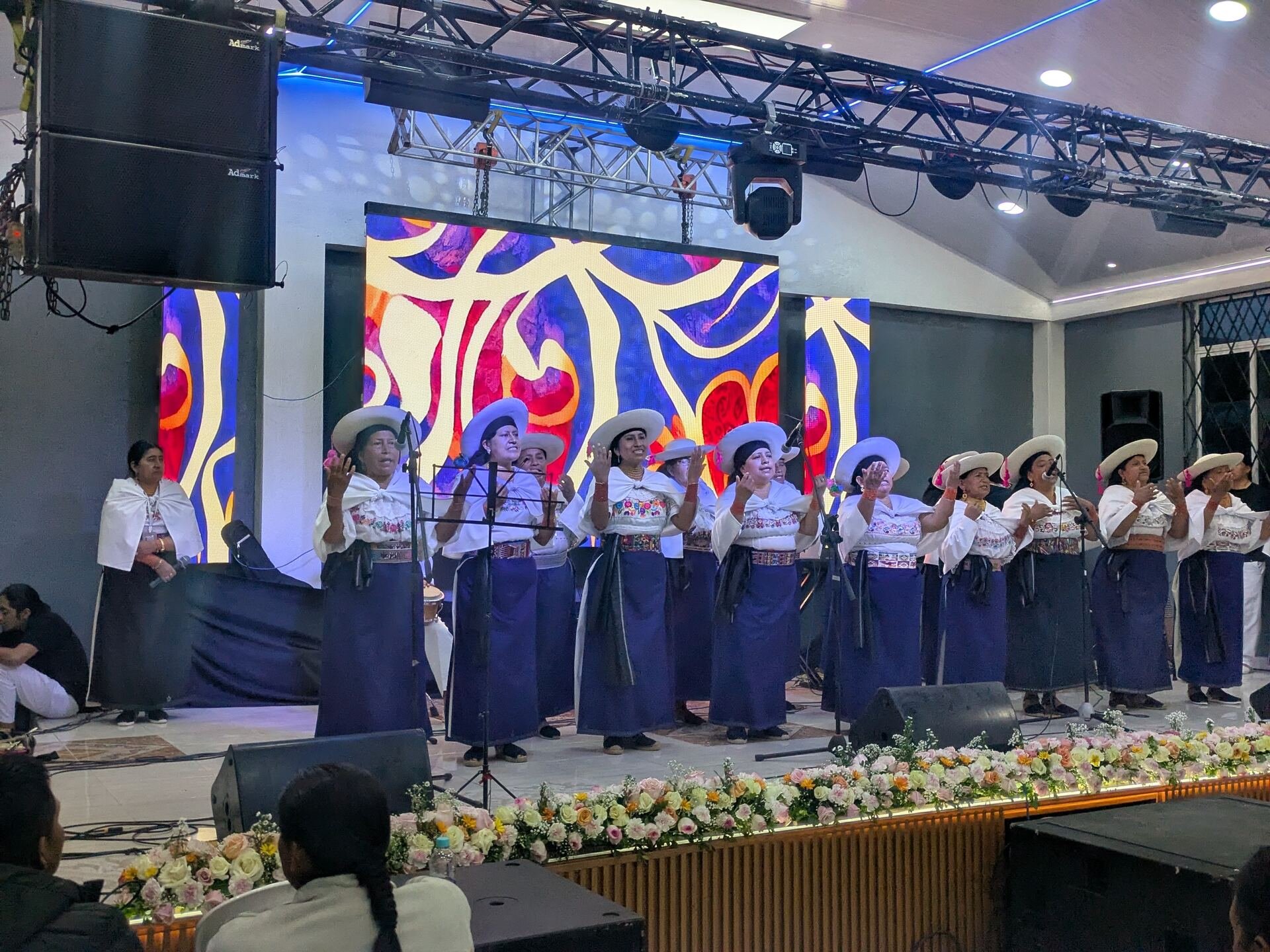 Coro folclórico cantando frente a pantallas LED con diseño artístico